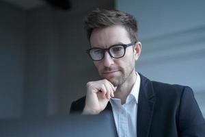 Focused German man family lawyer in formal wear thoughtfully looking at computer monitor photo