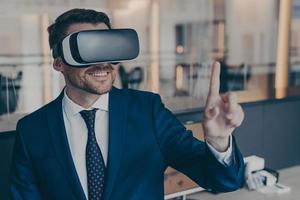 Smiling young finacier in formal suit enjoying spending time in virtual reality with VR headset photo