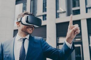 Smiling bearded businessman with stubble wearing VR glasses, viewing something in virtual reality photo
