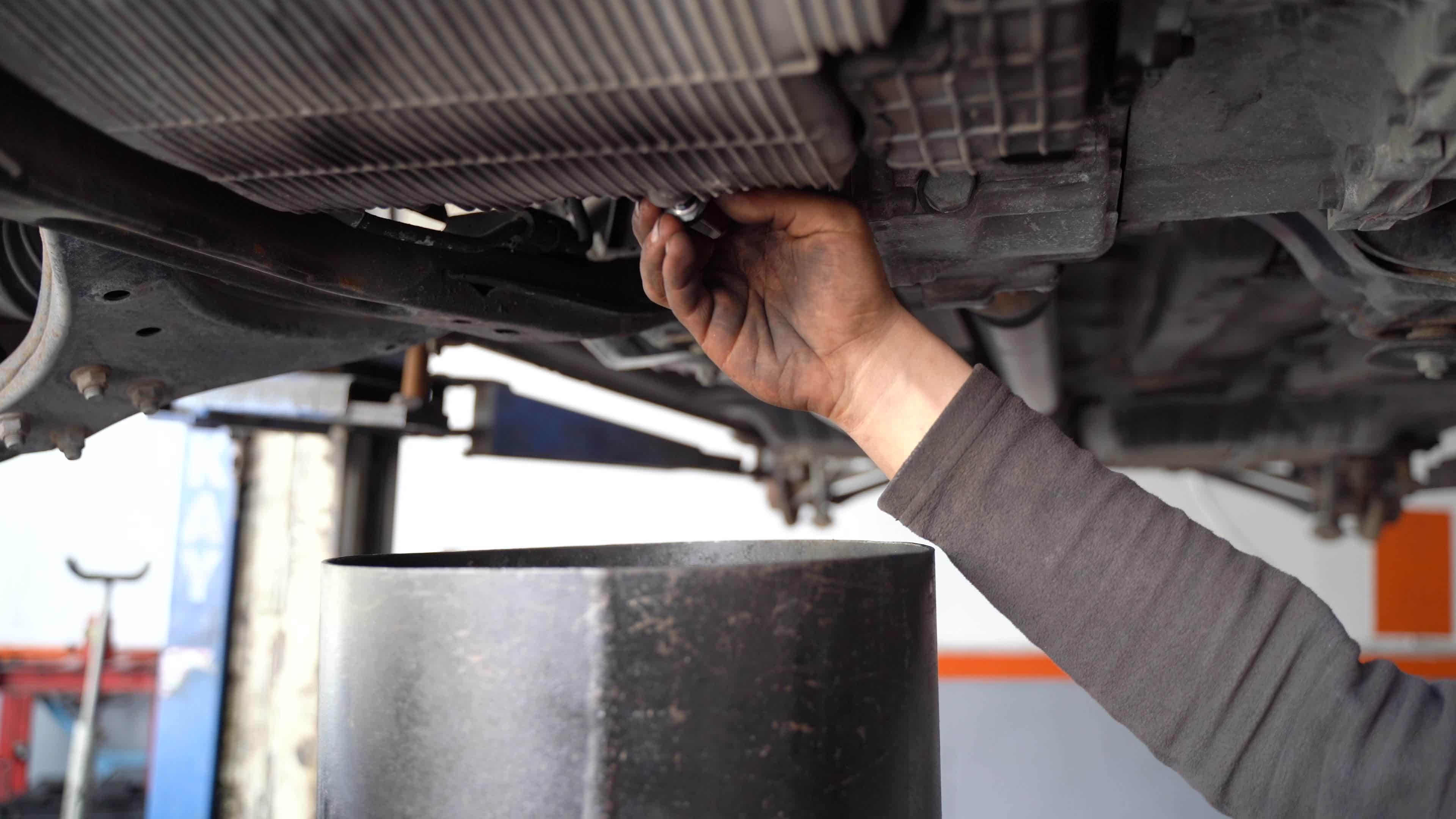 Car Oil Change Under The Car The Master Changes The Oil Of The Car car-oil-change-under-the-car-the-master-changes-the-oil-of-the-car
