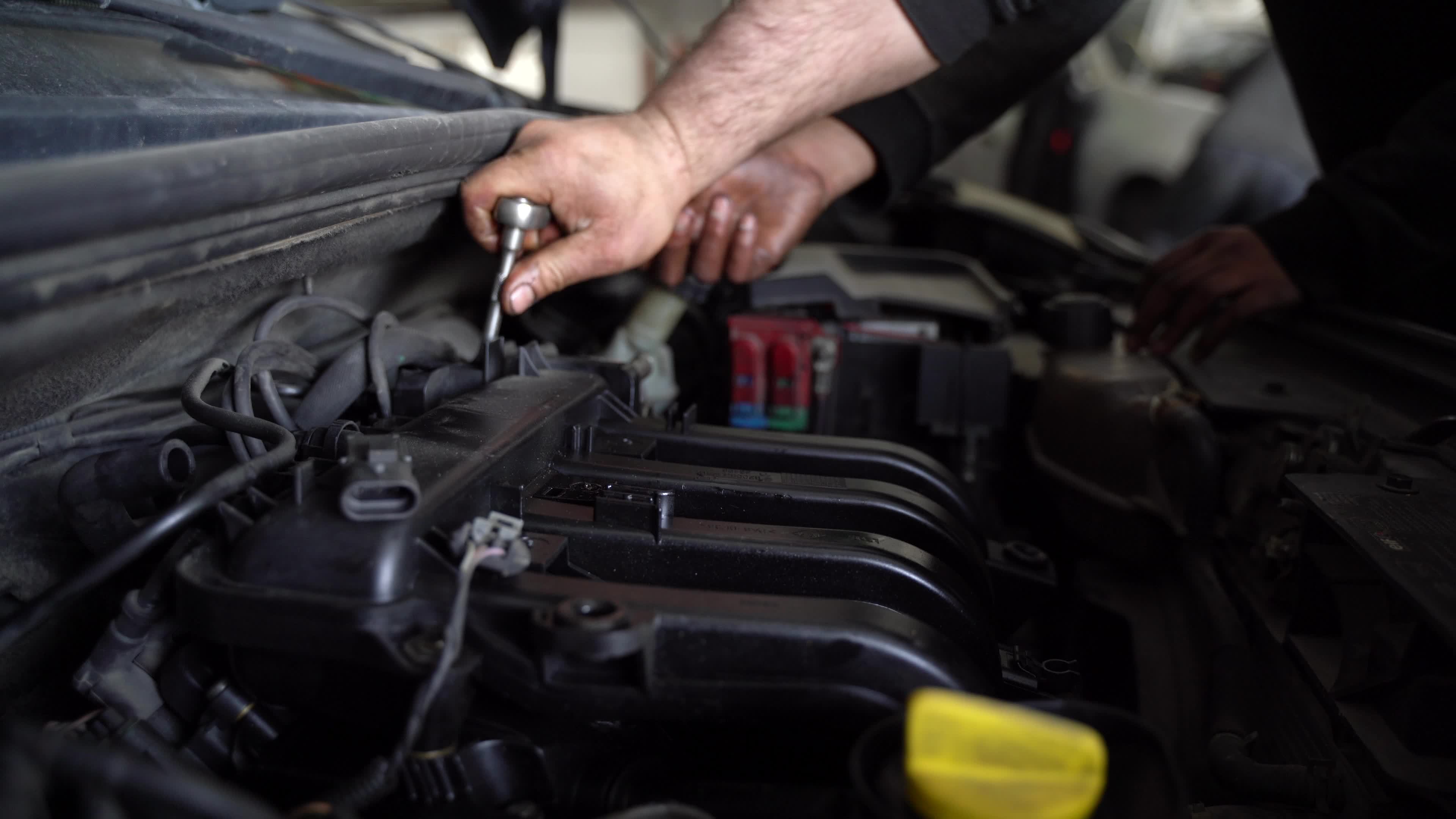 Car Engine Dismantling. The master loosens the screws with the help of