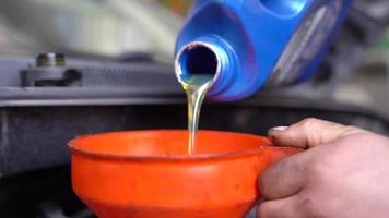 cambio de aceite de motor de coche. agregando aceite de motor nuevo al automóvil, cambiando el aceite del motor con la ayuda de un embudo. video