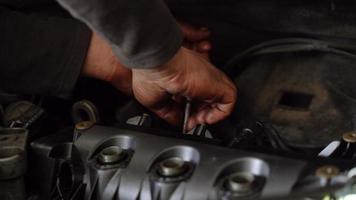 Working with the key on the car engine. Car repair master is working on the engine with the key. video