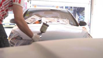 pintura do corpo do carro, pulverização de tinta. o mestre pinta o veículo com o pulverizador na mão.