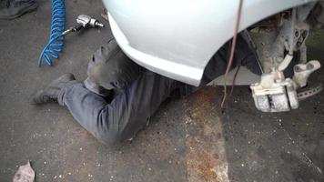 trabajando debajo del coche. el maestro que repara el automóvil trabaja acostado debajo del automóvil. video