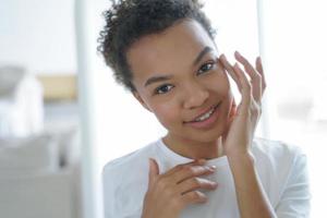 Biracial teen girl applying facial cosmetic serum for healthy face skin. Skincare beauty treatment photo
