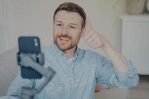 Young man showing thumbs up gesture while video chatting on phone photo