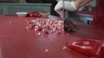ein Koch, der Fleisch verarbeitet. Der Koch schneidet das Fleisch mit einem Messer. Türkischer Döner zubereiten. Adana Kebab. video