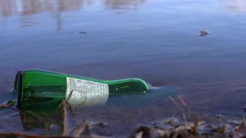 inquinamento dell'acqua, bottiglia di vetro nell'acqua. una mano prende la bottiglia di vetro dall'acqua, per prevenire l'inquinamento ambientale e idrico. previene l'inquinamento ambientale. video