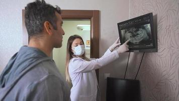 il dentista fornisce informazioni al suo paziente tramite radiografia. il dentista fornisce informazioni sulla bocca e sui denti al paziente attraverso i raggi X. video