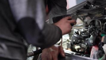 auto motor reparatie. de meester haalt met behulp van licht een onderdeel uit de motor van de auto. video