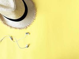 Woven hat and white ear phone on pastel yellow color background summer photo