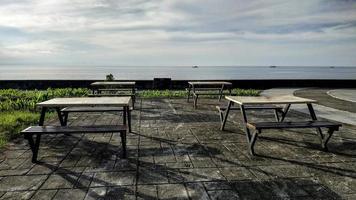 Rows of minimalist chairs and tables to relax enjoying the beach at Anjungan Vovasanggayu in Pasangkayu regency, Indonesia with a sea background photo