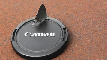 Pasangkayu regency, Indonesia, May 16 2022, Canon dslr camera lens cap with natural brown background, Butterfly on Canon dslr camera lens cap photo