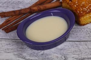 Condenced milk in the bowl with sinnamon and pastry photo