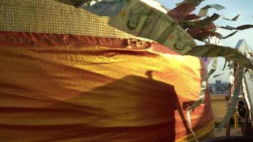 aht banknotes flutter on string against wrapped stupa, offering at Buddhist monastery. video