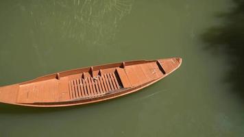 oude bruine houten boot voor anker voor de kust van de baai, zwaaiend in kalme golven. het vogeltje zat op de boeg van de boot. sereniteit in de ochtend bij de rivier video