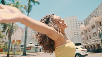 Young Latin woman spinning with open arms in the center of a city. 4k Cinematic. video