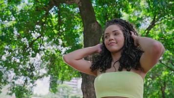 atractiva mujer latina caminando en el parque en un día soleado y sonriendo. el rostro de una hermosa mujer feliz en verano al aire libre. cámara lenta 4k video