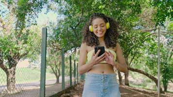 mulher latina usando smartphone no parque. menina brasileira. 4k cinematográfico.