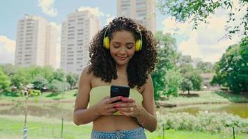 mulher latina usando smartphone no parque. menina brasileira. 4k cinematográfico.