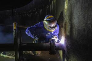 Welding male worker metal is part in machinery nozzle pipeline construction photo