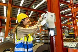 Portrait of woman Asian mechanic engineer worker wearing safety equipment beside the switch of electric machine system in manufacturing factory photo