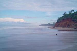 beach view with steep hills during the day with coconut trees photo