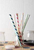 Colorful paper straws on wooden background. Event and party supplies. photo