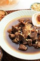 Selected Focus Rawon, Indonesian Traditional Beff Black Soup from East Java. Served on a Bowl wth Shrimp Cracker and Chilli Paste and Salted Egg photo