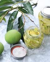 Homemade Manisan or Asinan Mangga is Candied Young Mango Pickles, Thin Sliced Mix with Water and Sugar and then Preserved on a Jar. Popular in Bogor, West Java. photo