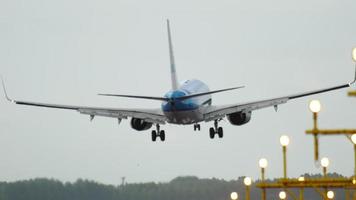 AMSTERDAM, THE NETHERLANDS JULY 27, 2017 - KLM Boeing 737 airliner landing on the runway in a crosswind with it's fuselage slightly skewed. View from the edge of the runway behind ALS masts video