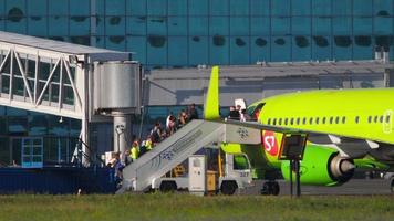 NOVOSIBIRSK, RUSSIAN FEDERATION JUNY 12, 2022 - Side view of passengers climbing a mobile ladder boarding an S7 airlines aircraft at Tolmachevo airport. Tourism and travel concept video