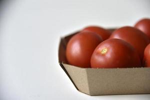 Cardboard box with ripe red tomatoes on a white background photo