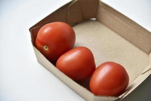 Cardboard box with ripe red tomatoes on a white background photo