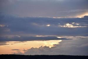 Evening clouds are blue pink and the forest horizon photo