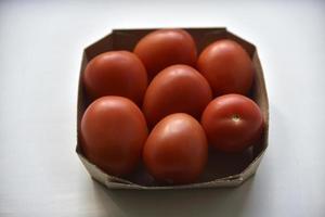 Cardboard box with ripe red tomatoes on a white background photo