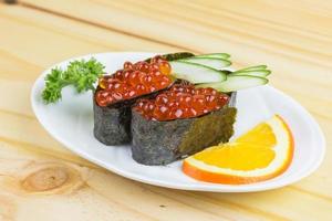 comida tradicional japonesa sushi ikura, sushi gunkan o huevas de salmón en rap de arroz japonés con algas marinas foto