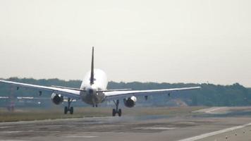 Rear view of jet plane landing. Glare of the sun reflection on the plane, haze on the runway video