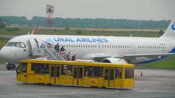NOVOSIBIRSK, RUSSIAN FEDERATION JULY 24, 2021 - Passengers descend the ladder from a Ural Airlines plane. Many people in masks and with suitcases travel. Go down. Arrival of a passenger video