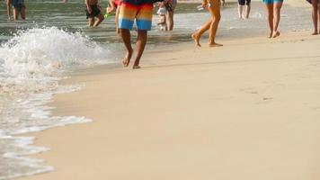 turisti che camminano a piedi nudi sulla spiaggia di sabbia bagnata di nai harn, phuket video