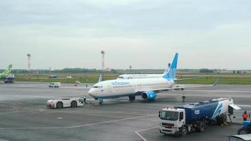 NOVOSIBIRSK, RUSSIAN FEDERATION JULY 24, 2021 - Tractor towing plane Pobeda Airlines on the runway at Tolmachevo airport. Tourism and travel concept, air flight. video