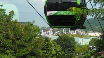 ilha de sentosa, singapore, 24 de novembro de 2018 - atração de montanha-russa na ilha resort sentosa e cabines de teleférico em primeiro plano video