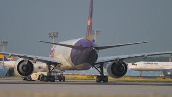 FRANKFURT AM MAIN, GERMANY JULY 19, 2017 - Cargo Boeing 777 of FedEx on taxiway at Frankfurt am Main Airport. Tractor towing aircraft on the runway before departure video