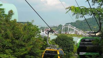 SENTOSA ISLAND, SINGAPORE NOVEMBER 24, 2018 - Roller Coaster attraction at Sentosa resort island and cable car cabins at foreground video