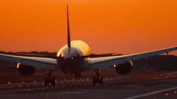 The wide bodied aircraft lands on the illuminated runway in the early morning video