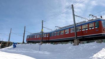 treno che passa dal monte Cervino a zermatt. veicolo ferroviario che corre verso la stazione di Gornergrat. paesaggio innevato contro il cielo blu nelle alpi durante l'inverno. video