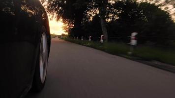 Tilt down low angle tire view wheel spin in real time with scenic nature sunrise over horizon background video