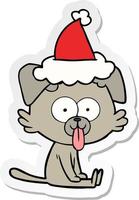 sticker cartoon of a sitting dog with tongue sticking out wearing santa hat vector