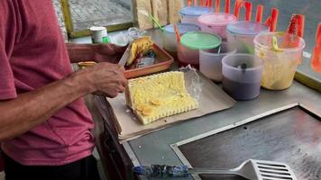 messa a fuoco selettiva. fare un dessert malese, toast toast indonesiano, martabak manis. il processo di preparazione del toast affettando sottilmente le banane come marmellata. video